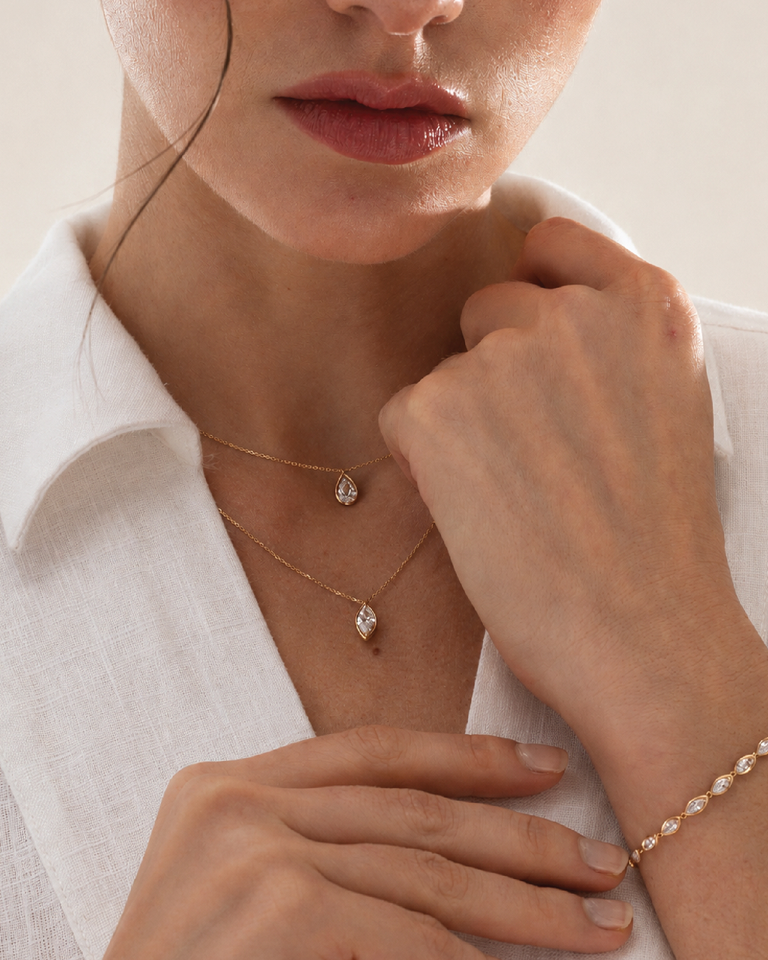 Close-up social image of layered Zorae necklaces and bracelet styled with a white shirt